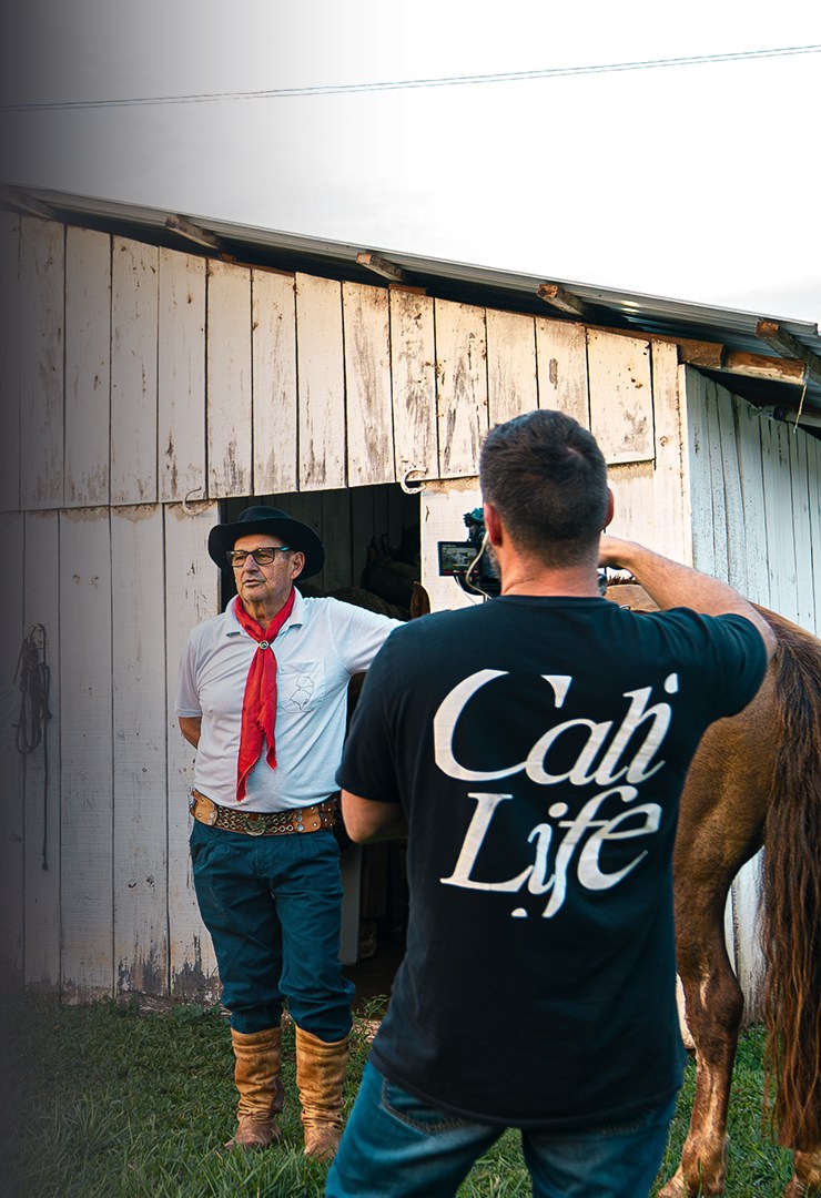 Celso and Fábio filming their first documentary in southern Brazil, beside a horse near a barn.